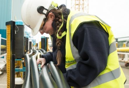 A young person in protective equipment operating machinery