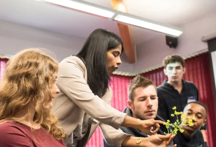 Teacher showing plant to plant science students in class